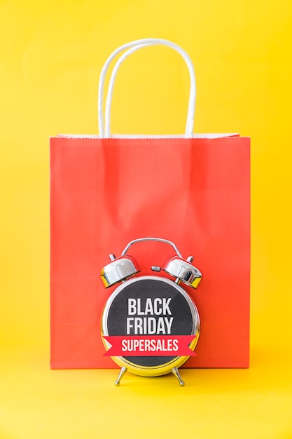 Concepto de black friday con despertador en frente de bolsa roja