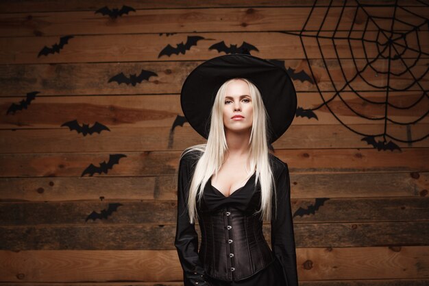 Concepto de bruja de Halloween feliz halloween bruja sexy sosteniendo posando sobre fondo de estudio de madera vieja