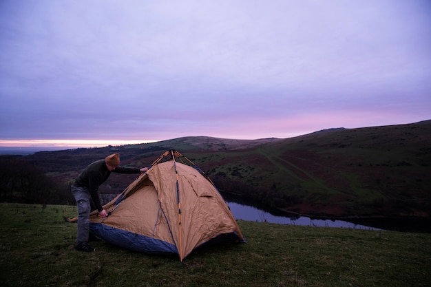 Concepto de camping de invierno con hombre montando carpa