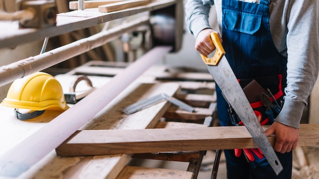 Concepto de carpintería con hombre trabajando con sierra