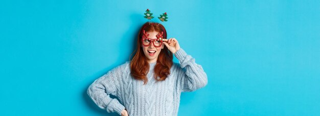 Concepto de celebración y fiesta de navidad linda pelirroja jovencita celebrando el año nuevo vistiendo xmas tre