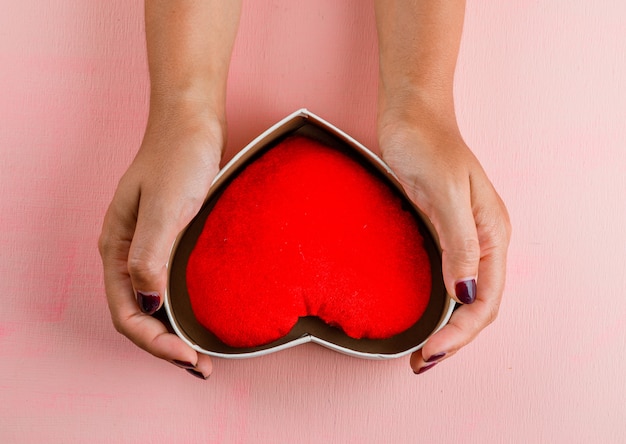 Concepto de celebración en mesa rosa plana lay. Mujer con caja de regalo.