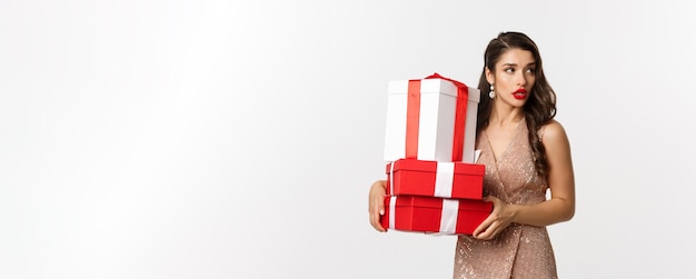 Foto gratuita concepto de celebración y navidad de año nuevo mujer joven atractiva en vestido elegante mirando hacia otro lado carr