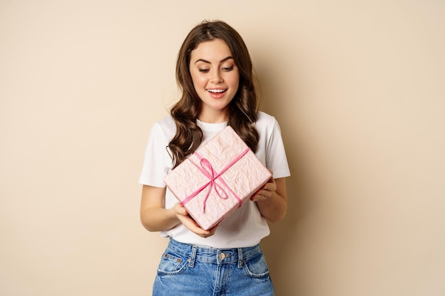 Concepto de celebración y vacaciones feliz mujer joven con regalo envuelto en caja rosa recibe presente...