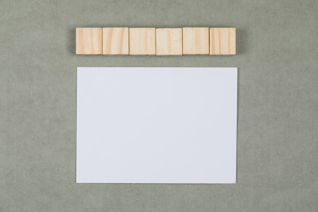 Concepto comercial y financiero con cubos de madera, papel en blanco sobre fondo gris plano lay.