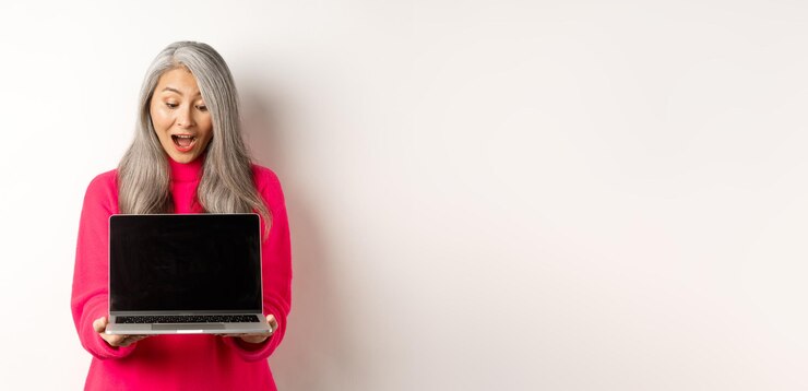 Foto gratuito el concepto de comercio electrónico asombró a la abuela asiática con cabello gris revisando la promoción en línea que muestra la computadora portátil b
