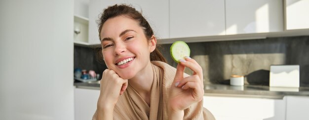 Foto gratuita concepto de comida y estilo de vida hermosa mujer cocinando en la cocina sosteniendo calabacines crudos y sonriendo