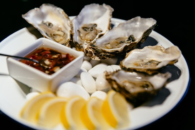 Concepto de comida Plato de ostras con salsa y limón. Marisquería.