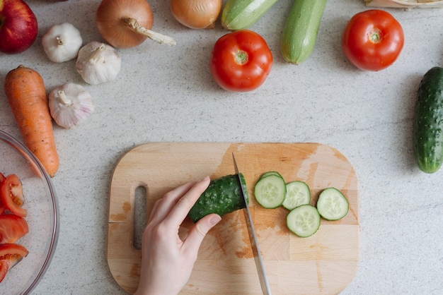 Concepto de comida sana con mujer cortando pepino