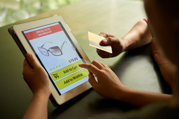 Concepto de compra en línea de dos personas irreconocibles que agregan gafas de sol al carrito en la tableta