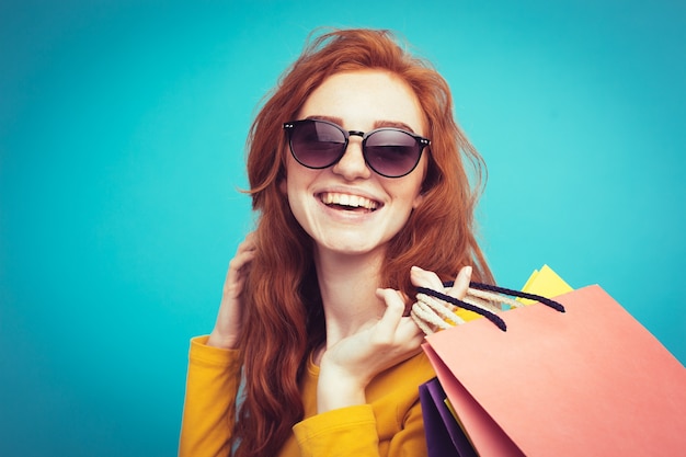 Concepto de Compras - Close up Retrato joven hermosa atractiva redhair niña sonriente mirando a cámara con bolsa de la compra. Fondo De Pastel Azul. Copie el espacio.