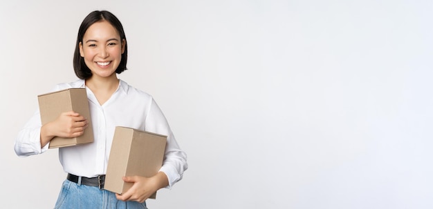 Concepto de compras y entrega joven mujer asiática feliz posando con cajas y sonriendo de pie