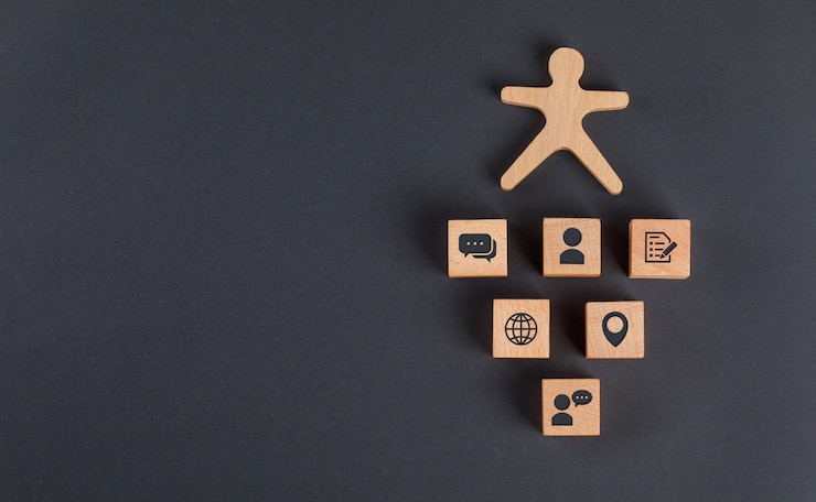 Foto gratuito concepto de comunicación con iconos en cubos de madera, figura humana en la mesa gris oscuro plano lay.
