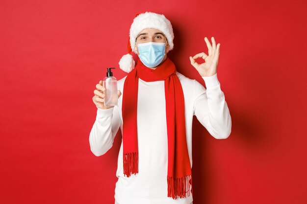 Concepto de covid navidad y vacaciones durante la pandemia hombre atractivo con sombrero de santa y máscara médica ...