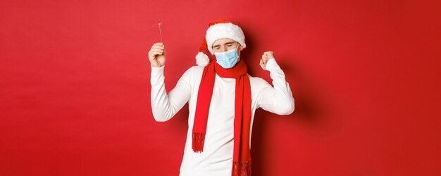 Concepto de covid navidad y vacaciones durante la pandemia hombre feliz celebrando el año nuevo en ropa de fiesta