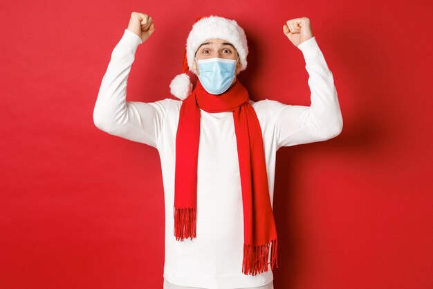 Concepto de covid navidad y vacaciones durante la pandemia retrato de hombre feliz con sombrero de santa y médico ...