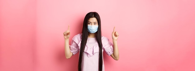 Concepto de cuarentena y estilo de vida de coronavirus hermosa mujer asiática con máscara médica estéril señalando