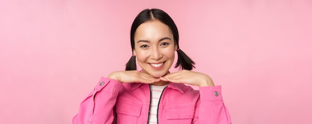 Concepto de cuidado de la piel y cosmetología Hermosa chica asiática sonriendo y riendo mostrando una piel facial limpia y saludable posando sobre fondo rosa Copiar espacio