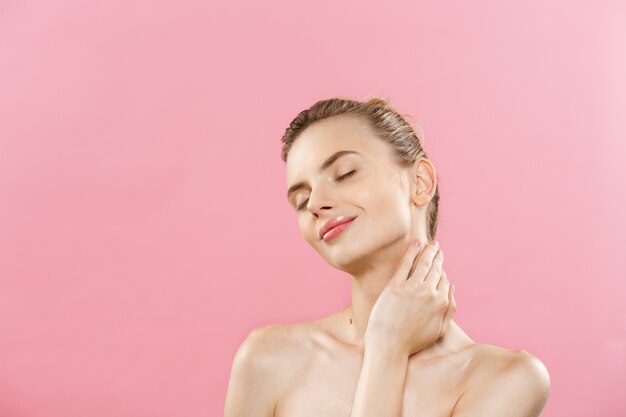 Concepto de cuidado de la piel - Encantadora mujer caucásica joven con maquillaje perfecto composición de fotos de niña morena. Aislado en fondo de color rosa con espacio de copia.