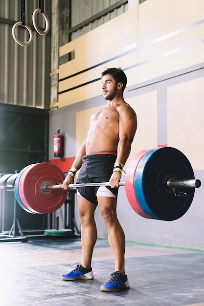 Concepto de culturismo con hombre entrenando con barra de pesas