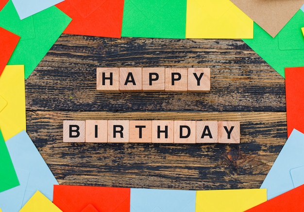 Concepto de cumpleaños con sobres de colores, cubos de madera sobre fondo de madera plana lay.