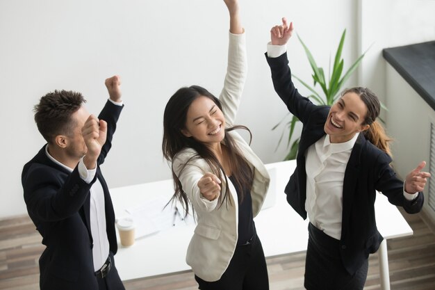 Concepto de danza de la victoria, diversos compañeros de trabajo entusiasmados celebrando el éxito empresarial