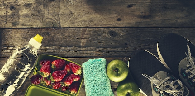 Concepto Del Deporte De La Vida Saludable. Zapatillas con manzanas, toallas y botellas de agua sobre fondo de madera. Espacio De La Copia.