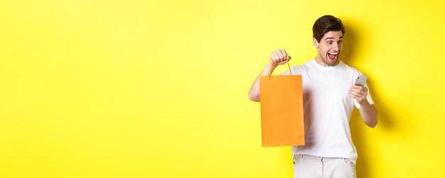 Concepto de descuentos en banca en línea y devolución de efectivo hombre sorprendido mostrando bolsa de compras y mirando feliz