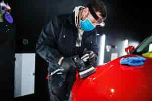 Foto gratuita concepto de detalle del automóvil hombre con máscara facial con pulidor orbital en el taller de reparación puliendo un automóvil todoterreno naranja