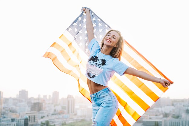 Concepto para el día de la independencia con chica en techo sujetando bandera