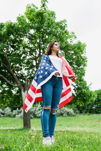 Concepto para el día de la independencia con mujer y bandera americana enfrente de árbol