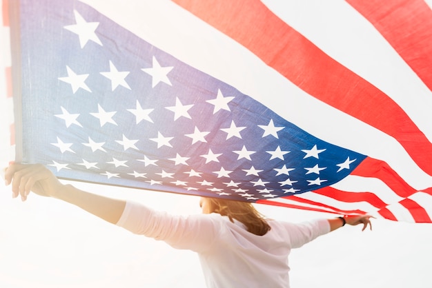 Concepto para el día de la independencia con mujer sujetando bandera sobre fondo de cielo