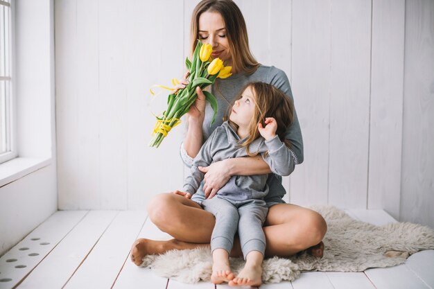 Concepto del día de la madre con madre e hija oliendo flores