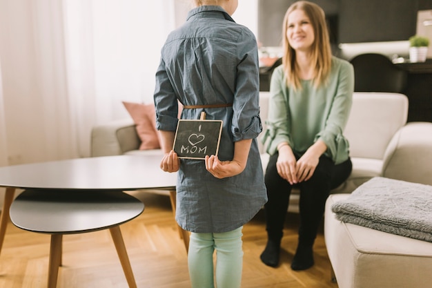 Concepto para el día de la madre con niña escondiendo tabla