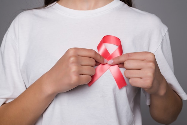 Concepto del Día Mundial contra el Cáncer de Mama, cuidado de la salud: la mujer vestía una camiseta blanca con una cinta rosa para la conciencia, el color del arco simbólico que se elevaba en las personas que viven con la enfermedad del tumor de mama