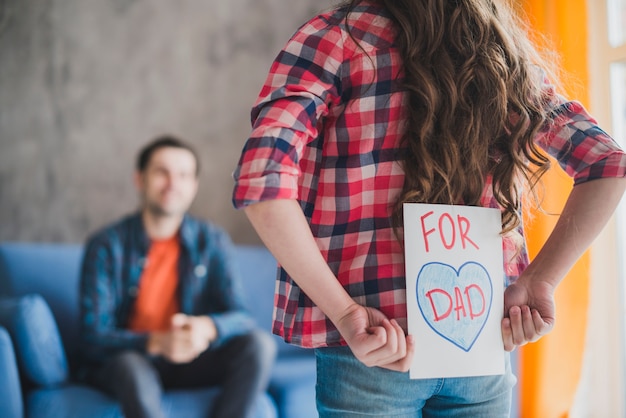 Concepto para el día del padre con hija escondiendo tarjeta dibujada a mano