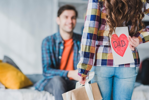 Concepto para el día del padre con hija escondiendo tarjeta