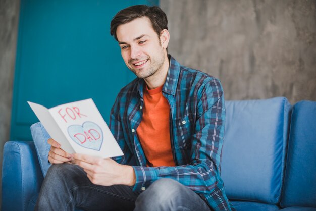 Concepto para el día del padre con padre leyendo tarjeta dibujada a mano