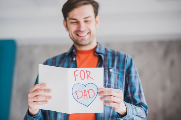 Concepto para el día del padre con padre sujetando tarjeta dibujada a mano
