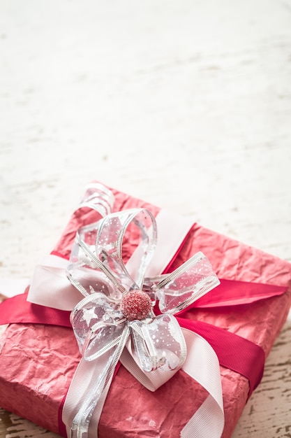 Concepto de día de San Valentín y día de la madre, caja de regalo roja con lazo y rosas sobre fondo de madera clara