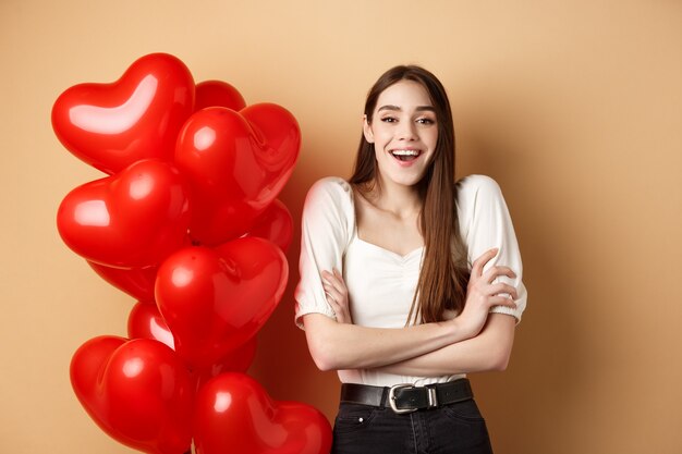 Concepto de día de san valentín hermosa mujer joven divirtiéndose riendo y sonriendo a la cámara de pie cerca ...