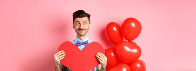 Foto gratuita concepto de día de san valentín hombre guapo sonriente con aspecto de ensueño dejado esperando el amor verdadero ingenio de novia