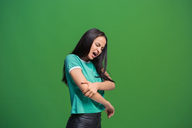 Concepto de dolor. Hermoso retrato femenino aislado sobre fondo verde. Joven mujer sorprendida emocional mirando a cámara. Las emociones humanas, el concepto de expresión facial.