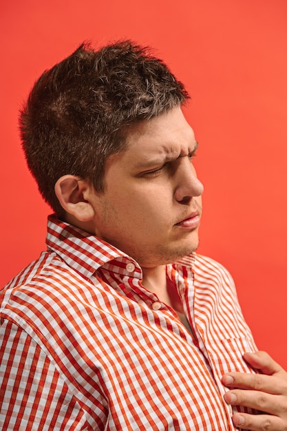 Concepto de dolor. Hermoso retrato masculino aislado en rojo