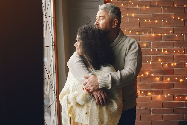 Concepto de edad y personas. Pares mayores con caja de regalo sobre fondo de luces. Mujer en una sudadera de punto blanco.