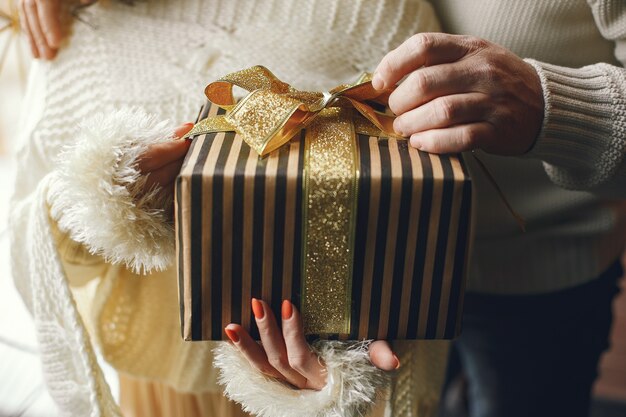 Concepto de edad y personas. Pares mayores con caja de regalo sobre fondo de luces. Mujer en una sudadera de punto blanco.