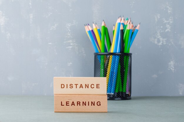Concepto de educación a distancia con bloques de madera con palabras, vista lateral de lápices de colores.