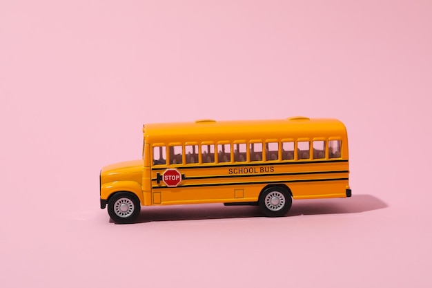 Concepto de educación escolar con autobús escolar sobre fondo rosa