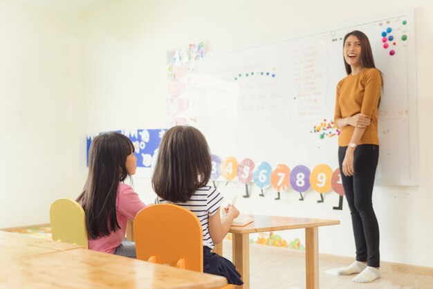 Concepto de la educación, de la escuela primaria, del aprendizaje y de la gente - grupo de niños de la escuela con el profesor que se sienta en sala de clase. Imágenes de estilo de efecto vintage.