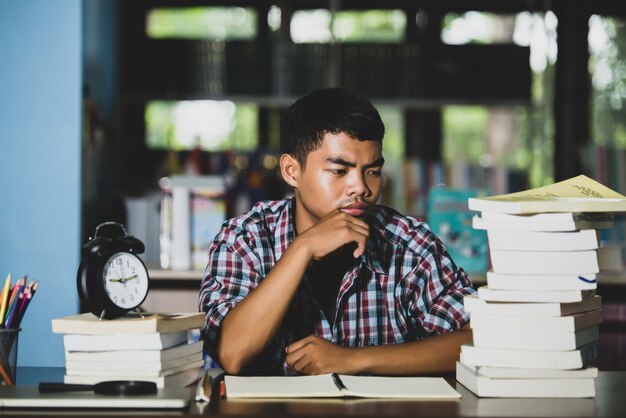 Concepto educativo: estudiante cansado en una biblioteca